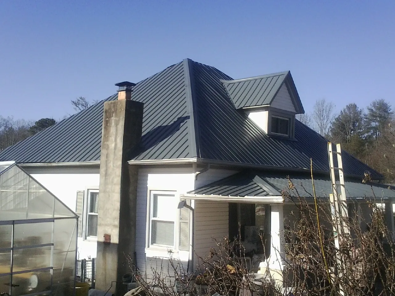 Dark blue standing seam metal roof on a white farmhouse with dormer — Slate & Tile Roof Repair by Roofing Brothers in Saint Michaels