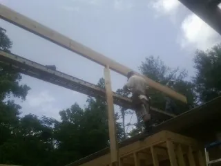 Carpenter setting a ridge beam over a new addition frame — Ice Dam Removal by Roofing Brothers in Saint Michaels