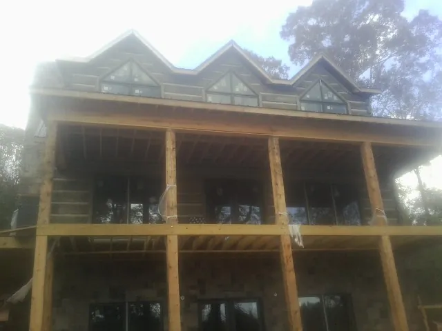 Dormers and porch framing on a large log home under construction — Roof Coating work by our crew in Saint Michaels