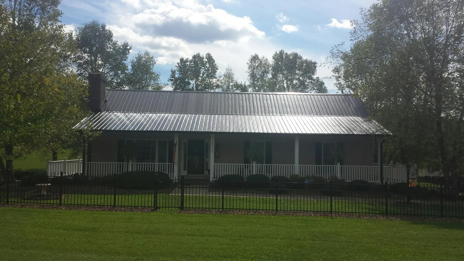 Gray metal roof on a brick ranch with a full width front porch — Gutter Guard Installation work by our crew in Saint Michaels