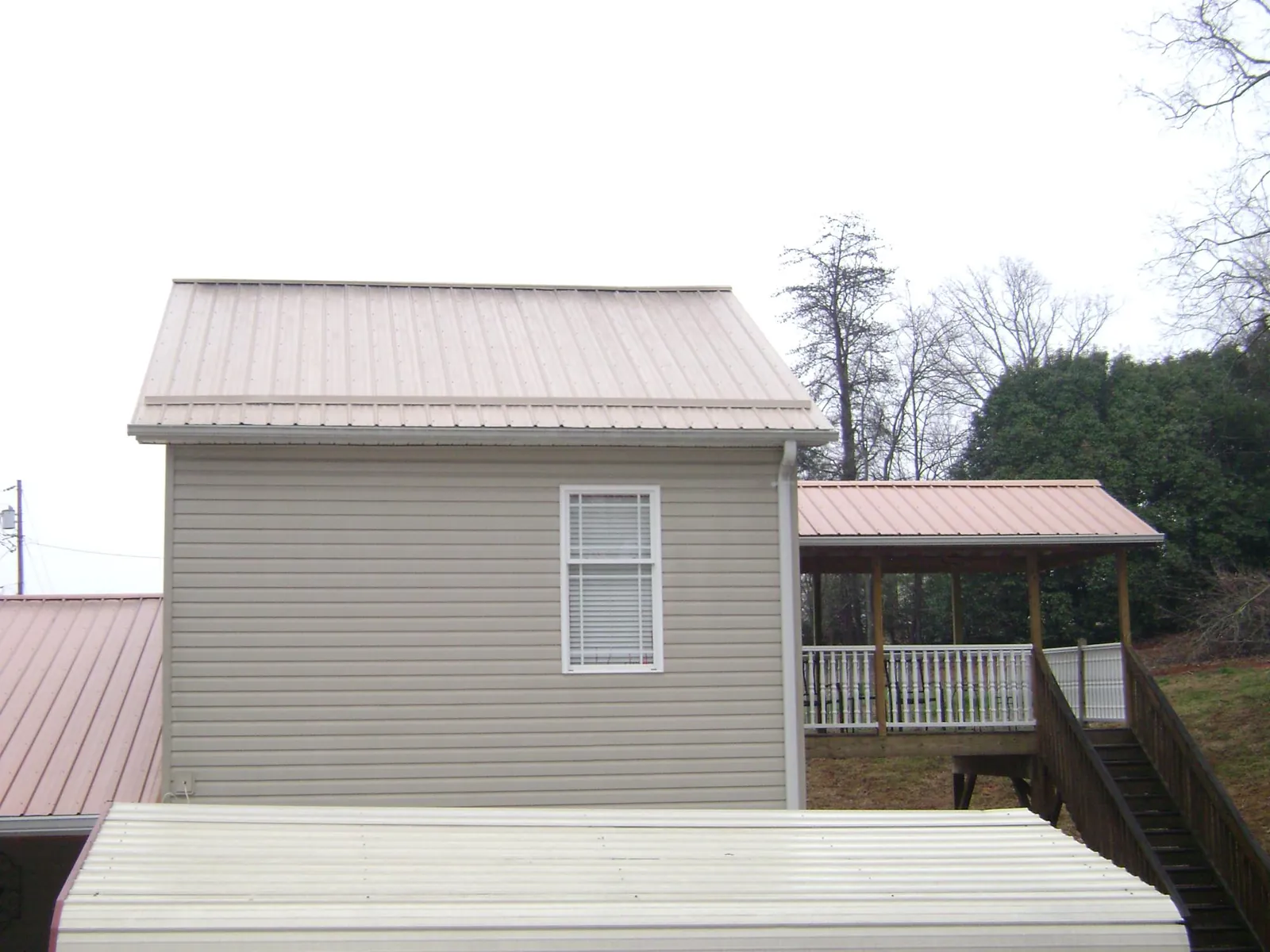 Tan metal roofs on a two story addition and attached porch, from a Roof Replacement job in Saint Michaels
