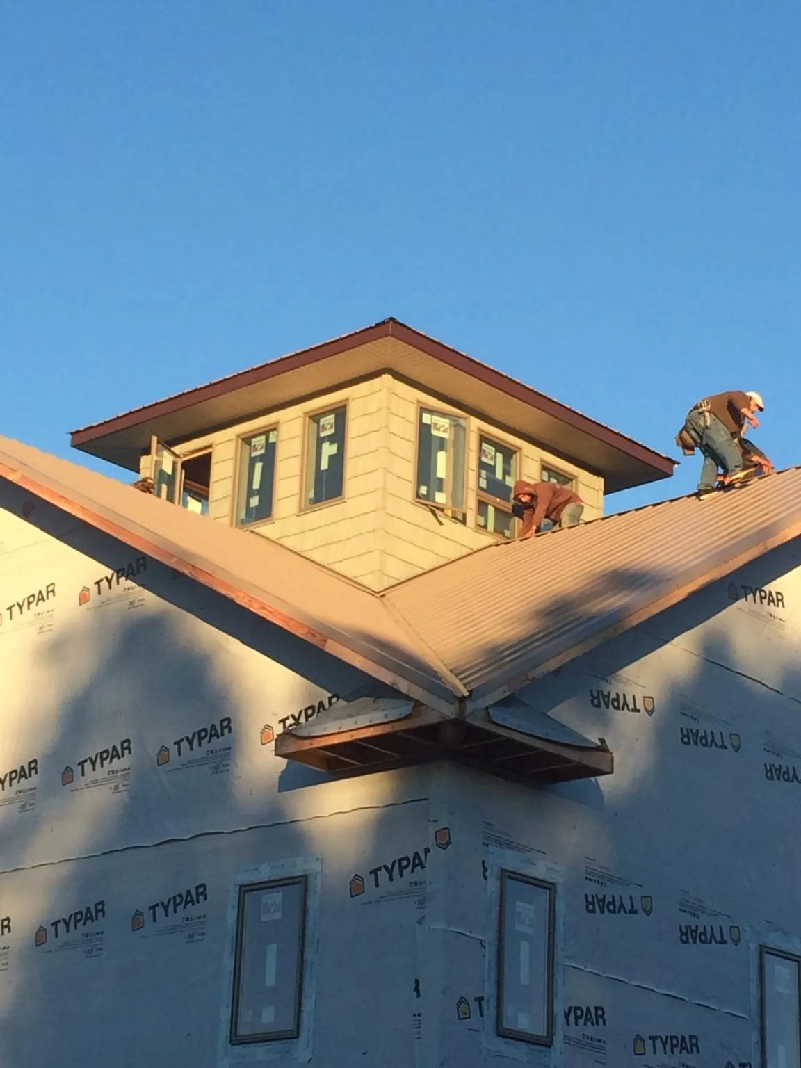 Roofers working around a rooftop cupola on a new metal roof at sunset — Roof Waterproofing in Saint Michaels by Roofing Brothers